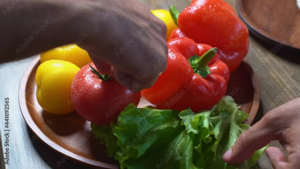 spread tomatoes,cucumbers,lettuce and sweet pepper on wooden round cutting board spread tomatoes,cucumbers,lettuce and sweet pepper on wooden round cutting board