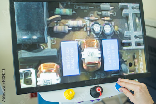 Woman examines microcircuits on a special apparatus for reading the visually impaired.