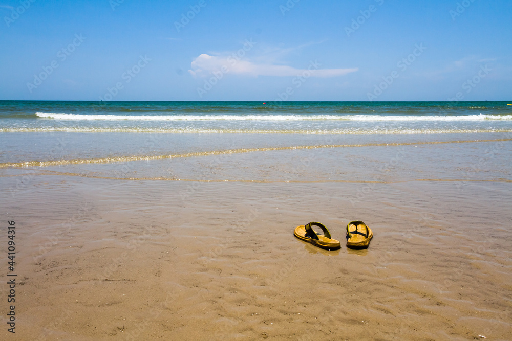 Old flip-flops on the beach against the blue sky in summer