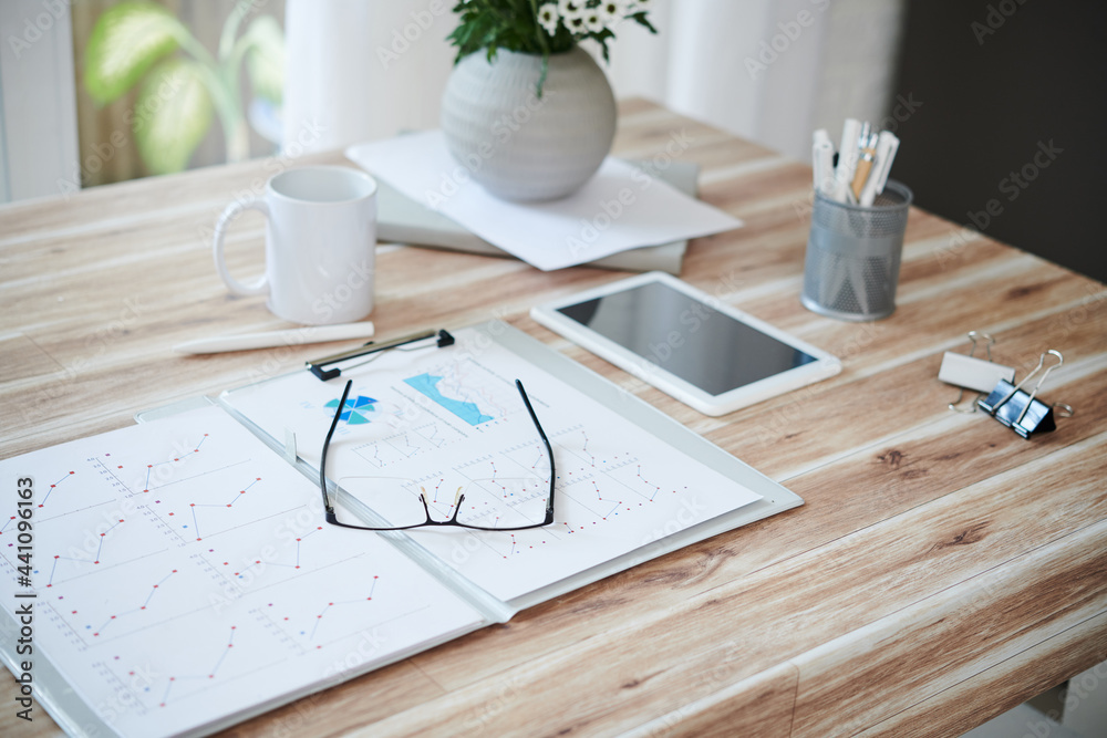 Opened folder with sales reports and glasses on table of entrepreneur Opened folder with sales reports and glasses on table of entrepreneur