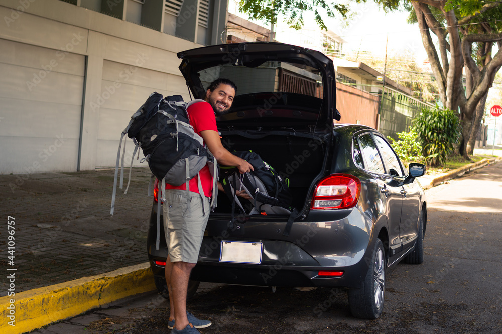 Man carrying a suitcase into the trunk of the car, ready to go on a trip Man carrying a suitcase into the trunk of the car, ready to go on a trip