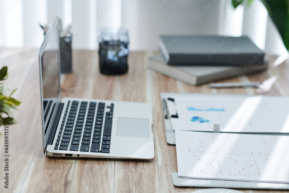 Reports with charts and diagrams and opened laptop on home office desk, selective focus Reports with charts and diagrams and opened laptop on home office desk, selective focus