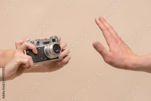 Do not shoot concept. No photo. One person with photo camera in hand and stop gesture by another hand close up. Personal space.