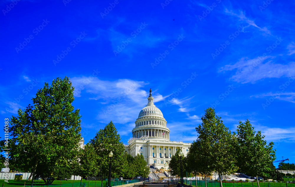 The white Capital building with a dome, green trees and blue sky.Famous buildings in Washington, D.C., U.S.A. October 2016.