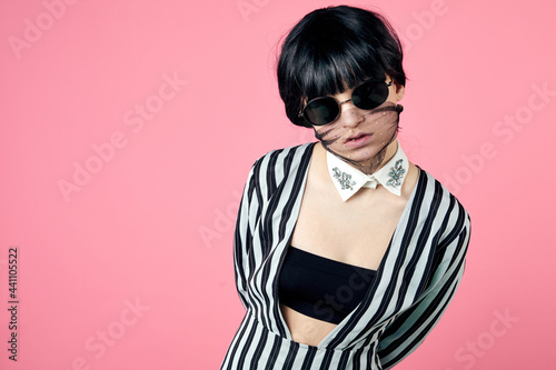 Young woman wearing trendy fashion outfit during coronavirus outbreak. Style look including protective stylish face mask and glasses. Studio shot.