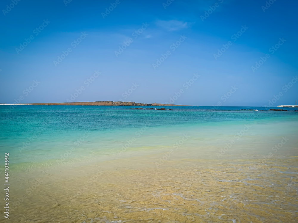 Calm ocean on Boa Vista Island, Cape Verde. Tropical climate, tranquil sea, clear blue sky and a perfect vacation. Selective focus on the horizon, blurred background.