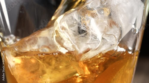 Pouring fresh iced tea into the glass with ice cubes, sliced lemons. Healthy refreshing lemonade for detoxification, sweet tasty soft drink or cold aromatic beverage for summer time in slow motion