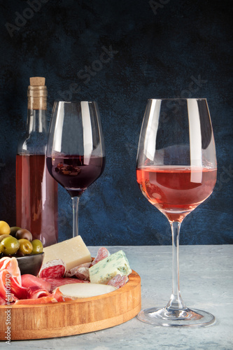 Wine, cheese, charcuterie and olives. Italian antipasti buffet with glasses of rose and red wine with blue cheese on a dark background with a place for text