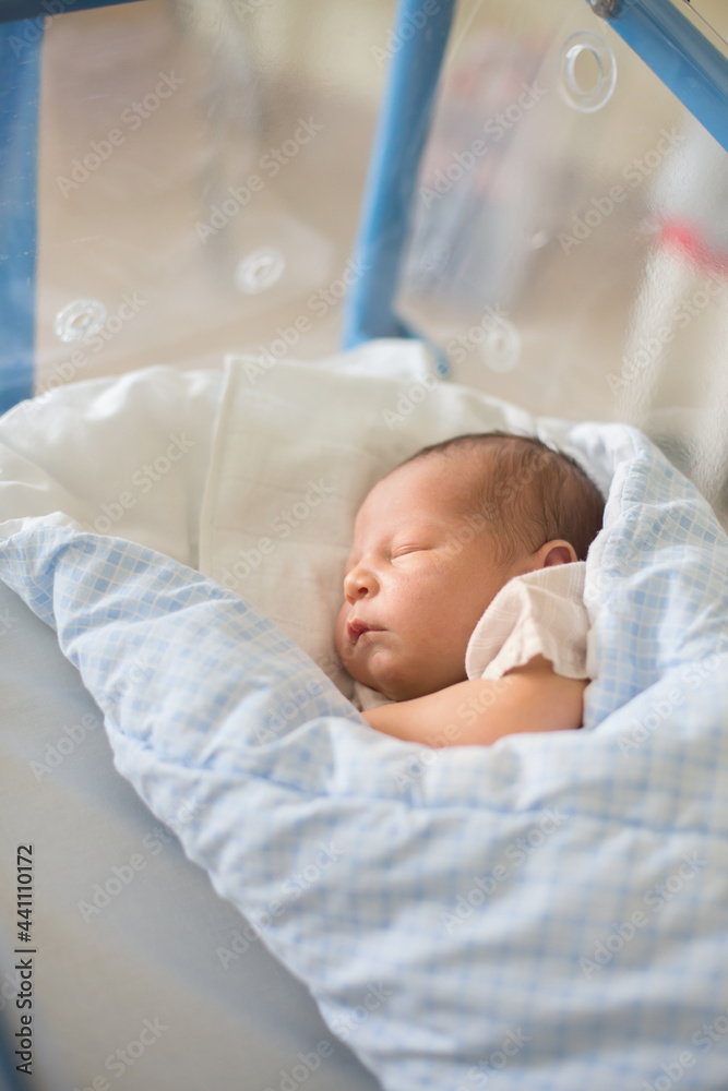 Newborn baby laying in crib in prenatal hospital Newborn baby laying in crib in prenatal hospital