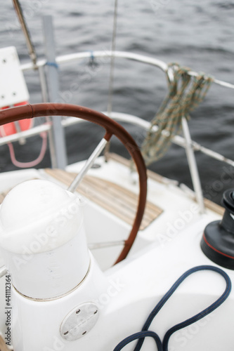 Boat trip on the river. Details about the sailing yacht. In the summer we go by boat. A white yacht with full sails. Leisure, sports, recreation theme. Close-up view of the steering wheel.