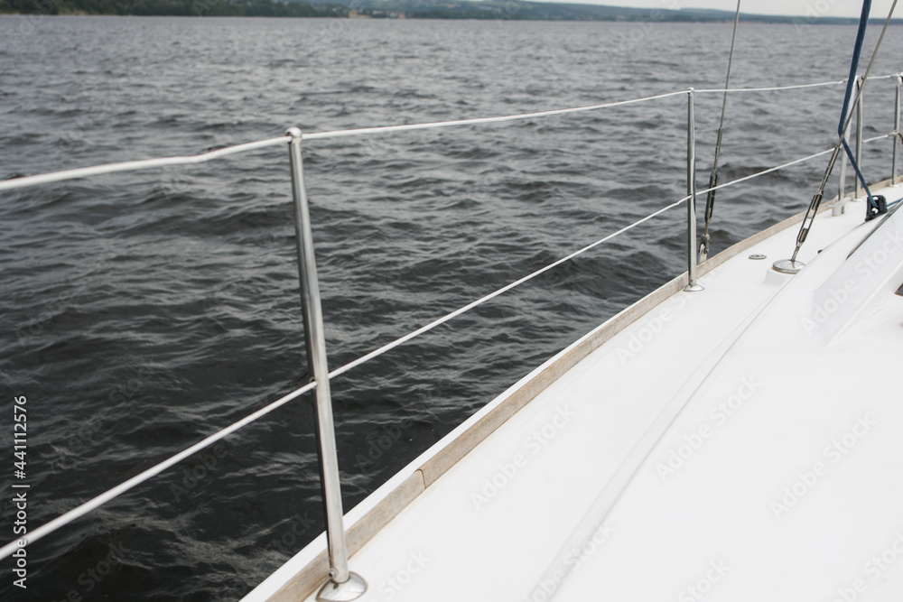Obraz premium Boat trip on the river. Details about the sailing yacht. In the summer, we go by boat. A white yacht with full sails. Leisure, sports, recreation theme. Close-up view of the metal railing.