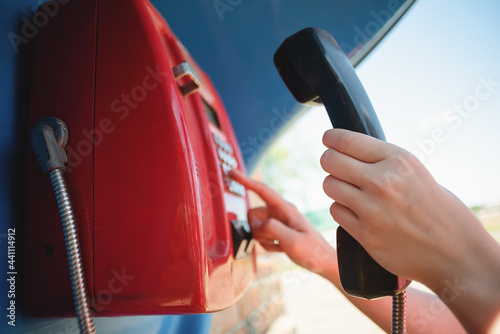 Woman is calling by the public payphone close up. photo