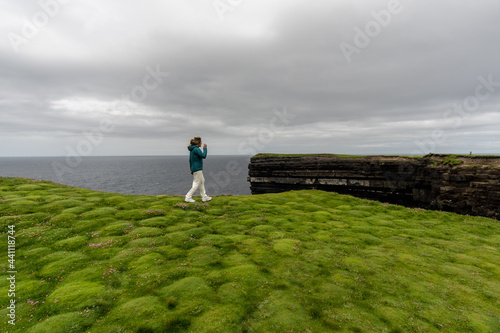 Woman walking on cliff at Downpatrick Head Ireland