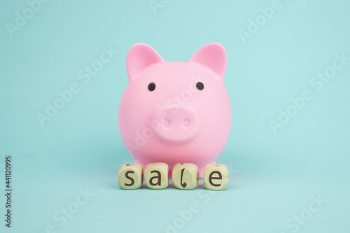 Pink piggy bank with geometric wood blocks cube adt text SALE on blue background. Saving money for sales of the year, black friday concept. photo