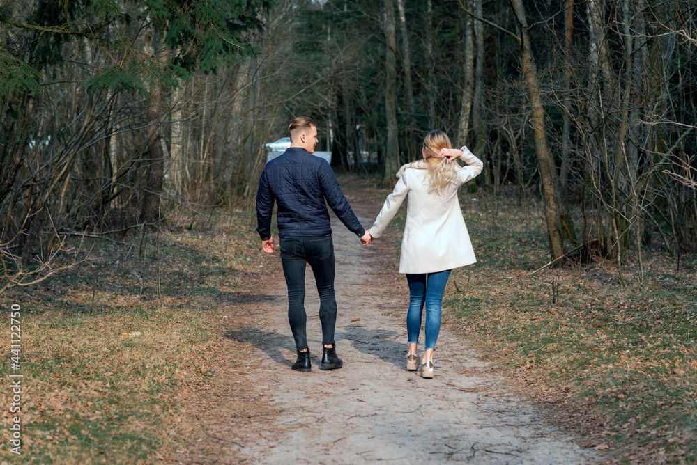 Fototapeta premium Beautiful loving couple going for a walk in a forest in the spring,autumn outdoors sunny day.Rear view.