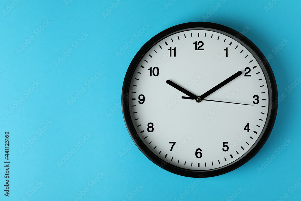 Standard black office clock on blue background Standard black office clock on blue background
