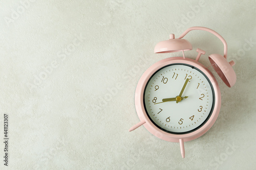 Pink alarm clock on white textured background