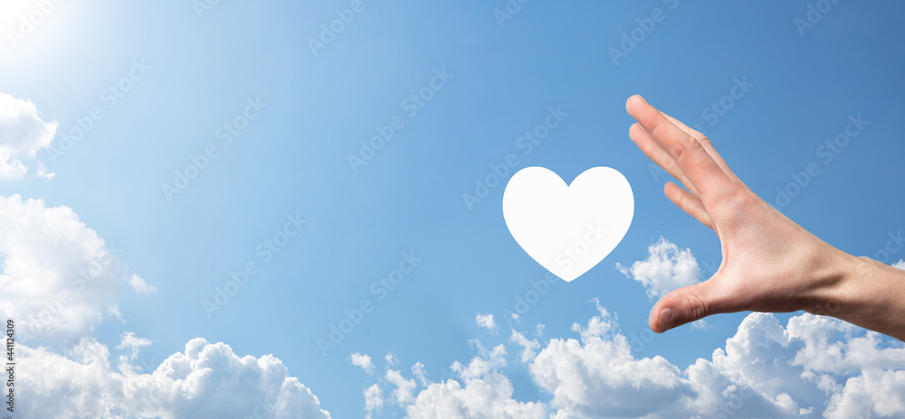 Male hand holding heart , like icon on blue background. Kindness, charity, pure love and compassion concept.Banner with copy space