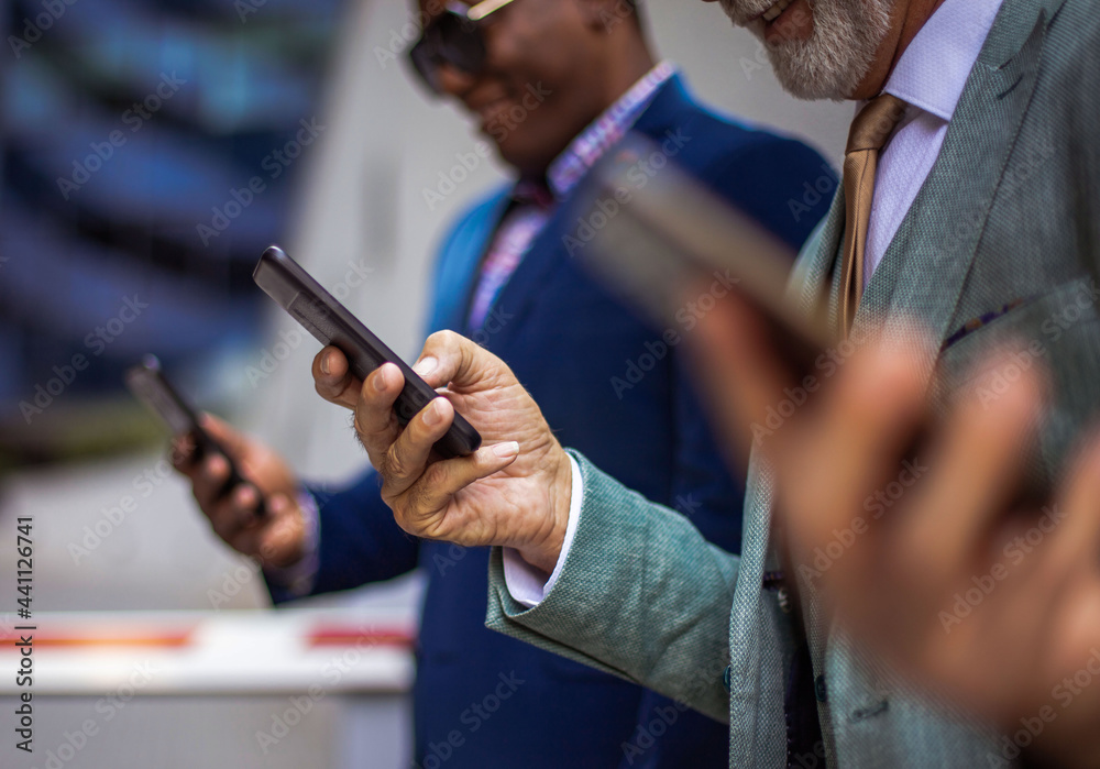 Three business men in the city standing on street and using mobile phones.  Focus is on background.