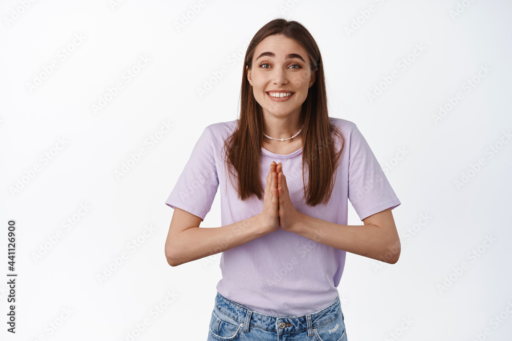 Image of young woman, friend ask for help, need favour, beg you with smiling cute face, asking for something, standing against white background Image of young woman, friend ask for help, need favour, beg you with smiling cute face, asking for something, standing against white background