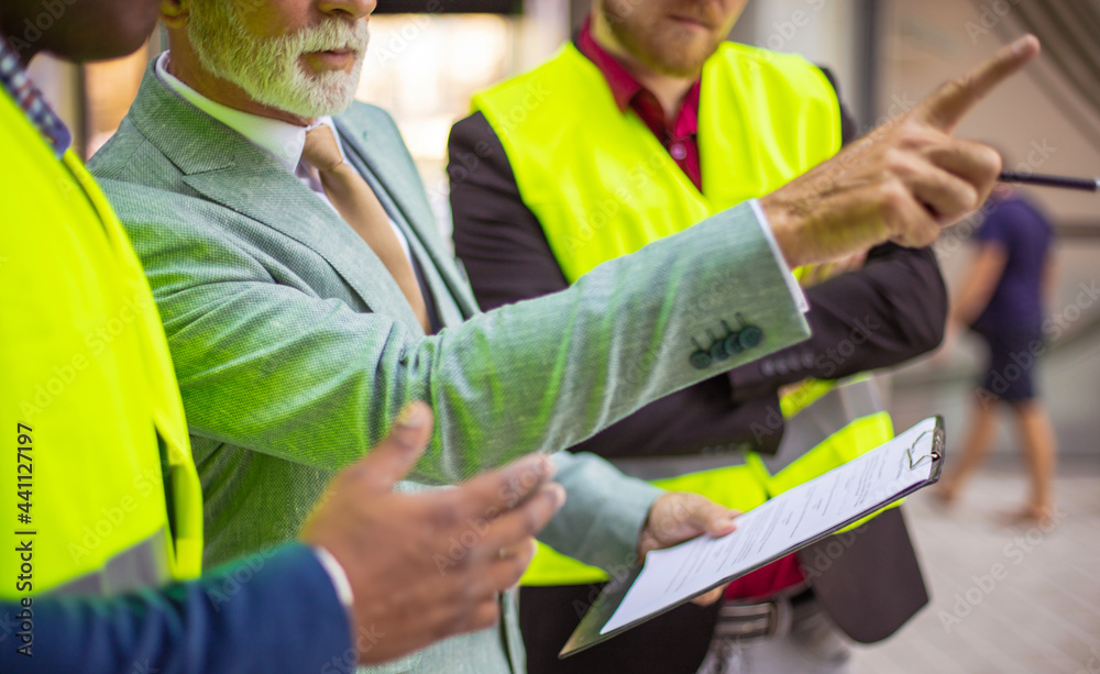 The construction site boss has a conversation with the architects and showing something. Close up. The construction site boss has a conversation with the architects and showing something. Close up.
