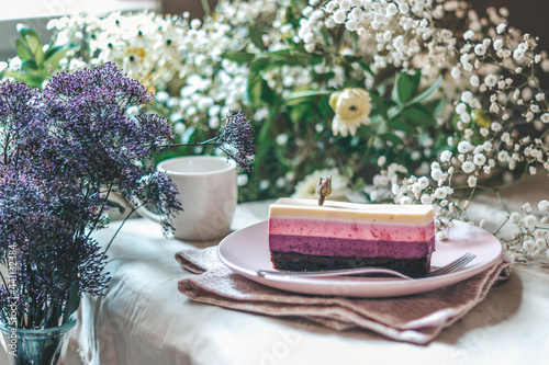 Close up on raspberry cake on a Nordic plate decorated with seasonal flowers