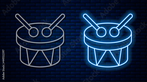 Glowing neon line Musical instrument drum and drum sticks icon isolated on brick wall background. Vector