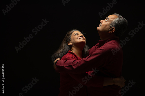 PORTRAIT OF A HAPPY COUPLE EMBRACING EACH OTHER AND LOOKING ABOVE