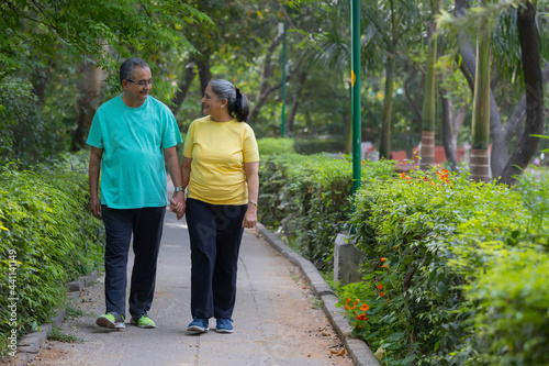A SENIOR COUPLE WALKING HAND IN HAND IN A PARK