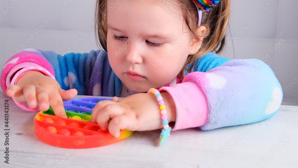 cute little girls with pop it sensory toy. little female presses colorful rainbow squishy soft silicone bubbles on white background. Stress and anxiety relief. Trendy fidgeting game. cute little girls with pop it sensory toy. little female presses colorful rainbow squishy soft silicone bubbles on white background. Stress and anxiety relief. Trendy fidgeting game.