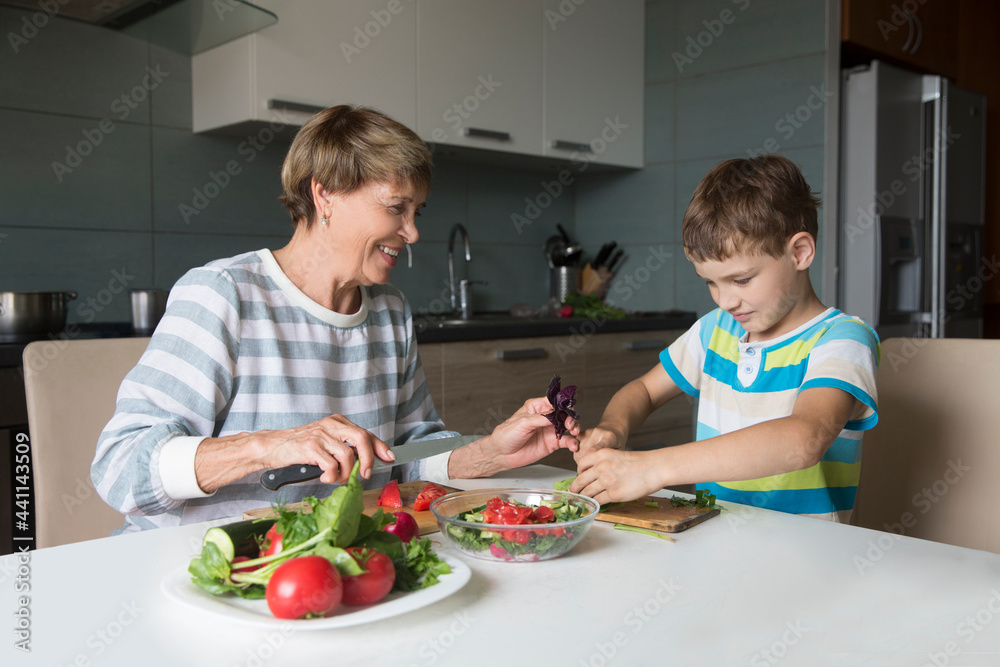 grandmother and grandson together make salad for lunch at home 