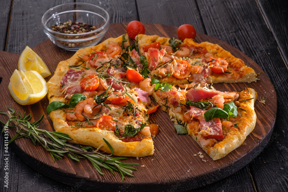 Pizza with shrimps, cheese, basil and tomatoes on a wooden background