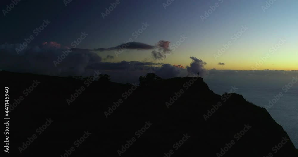 Aerial Panning Silhouette Shot Of Man On Mountain Top During Vacation, Drone Flying Over Sea During Sunset - Kauai, Hawaii Aerial Panning Silhouette Shot Of Man On Mountain Top During Vacation, Drone Flying Over Sea During Sunset - Kauai, Hawaii