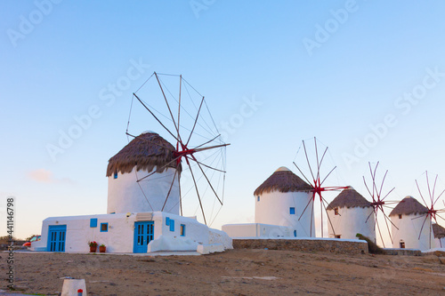 Windmills in a row from distance at dawn with partialy blue sky Mykonos island cyclades Greece