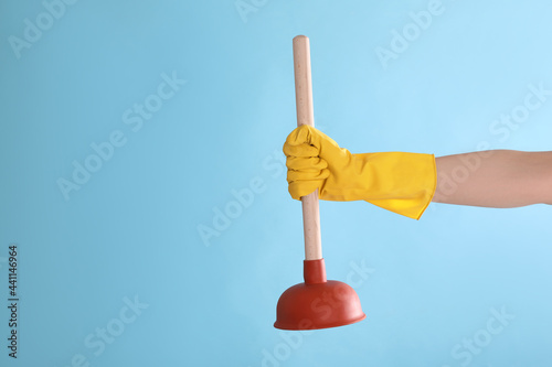 Photos Woman holding plunger on turquoise background, closeup