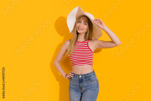 Young Woman In White Summer Hat Is Posing On Yellow Background