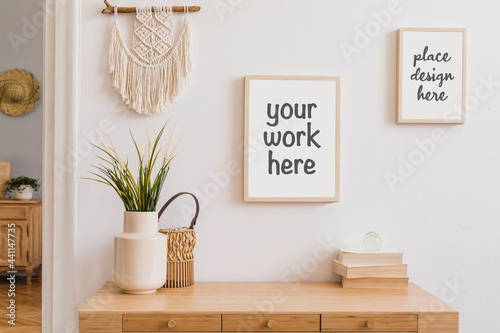 Fotografia Stylish composition of modern hall interior with elements of rustic and boho style with two mock up poster frames, wooden commode and other home accessories