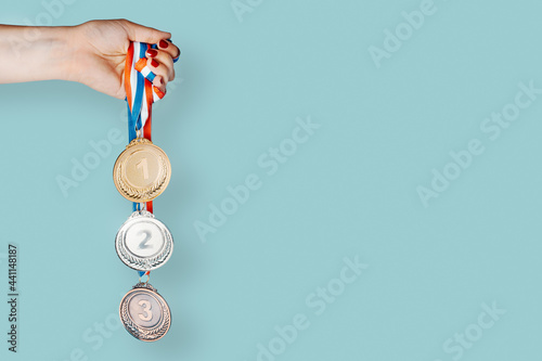 Woman's hand holding three medals (gold,silver,bronze).concept of award and victory.copy space