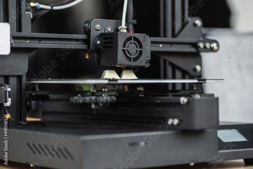 close up view of 3D printer creating plastic model on blurred background