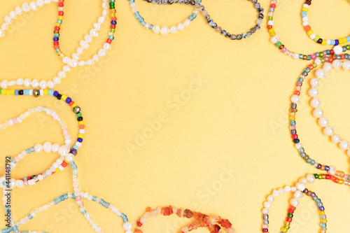 Necklaces and bracelets made from beads and pearls on a golden background. Border frame with copyspace.