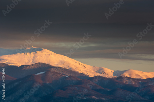 Golden sunset in winter over mountain covered in snow © Mihai