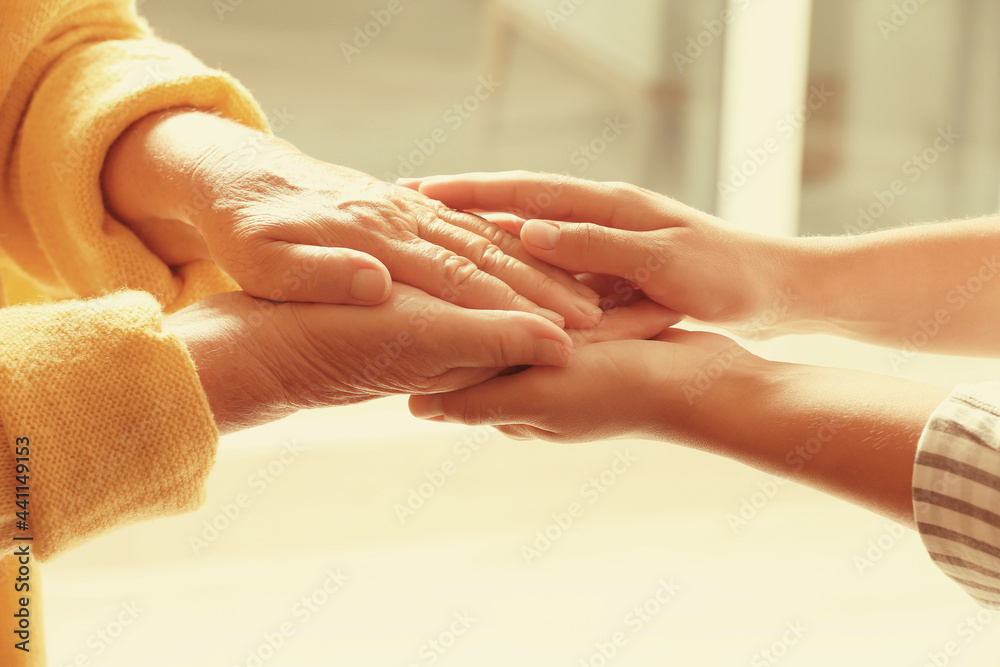 Naklejka premium Helping hands on blurred background, closeup. Elderly care concept