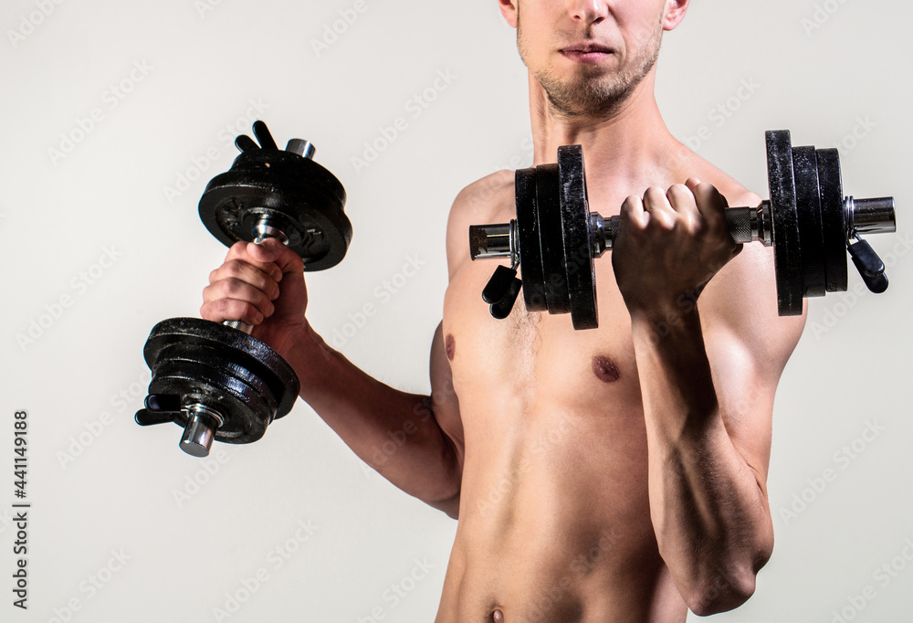 Man holding dumbbell in hand. Skinny guy hold dumbbells up in hands. A thin man in sports with dumbbells. Weak man lift a weight, dumbbells, biceps, muscle, fitness. Nerd maleraising a dumbbell