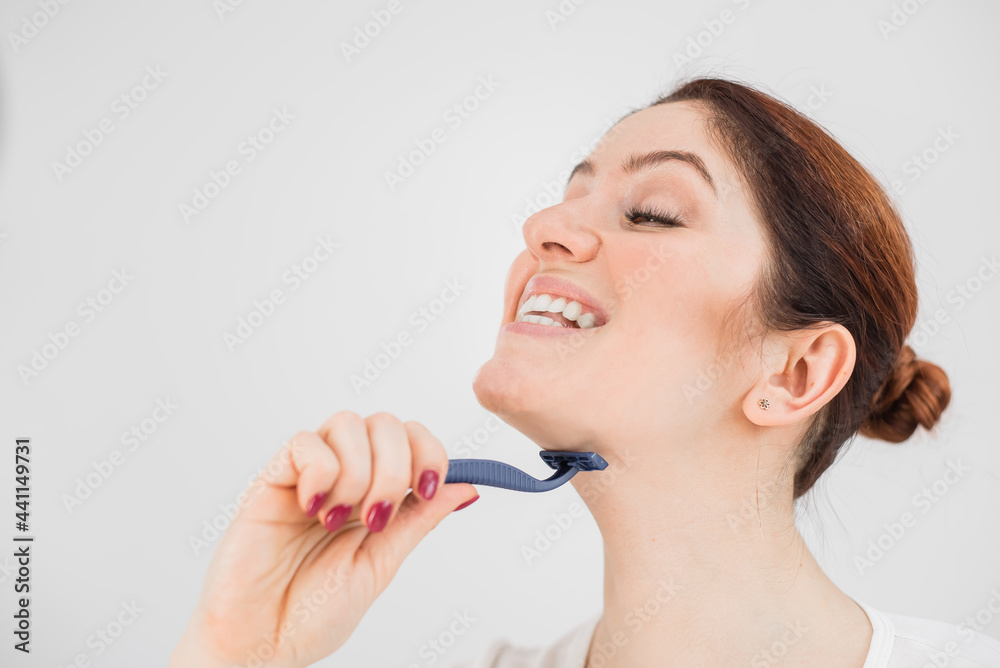 Caucasian funny woman shaves her face with a straight razor on a white background. Copy space.