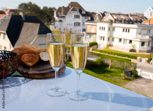 Drinking of brut champagne sparkling wine in flute glasses on outdoor bistro terrace in France