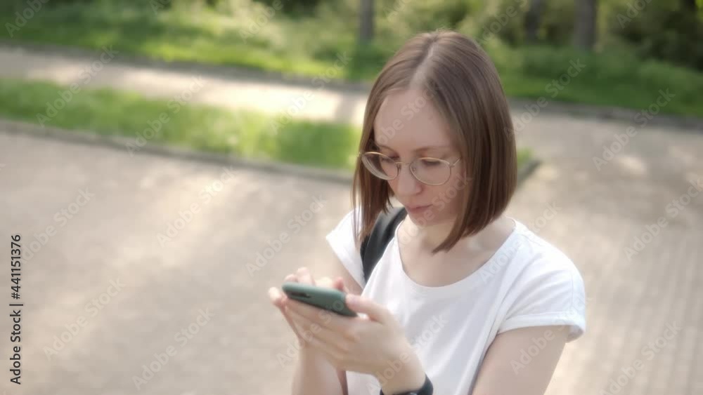 Attractive young girl in glasses chatting with boyfriend using a smartphone. Attractive young girl in glasses chatting with boyfriend using a smartphone.
