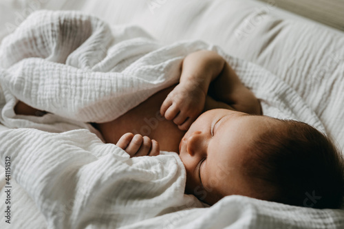 Quadro su tela Newborn baby sleeping covered with white muslin blanket.