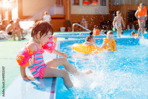 Fotografie Little girl playing in outdoor swimming pool