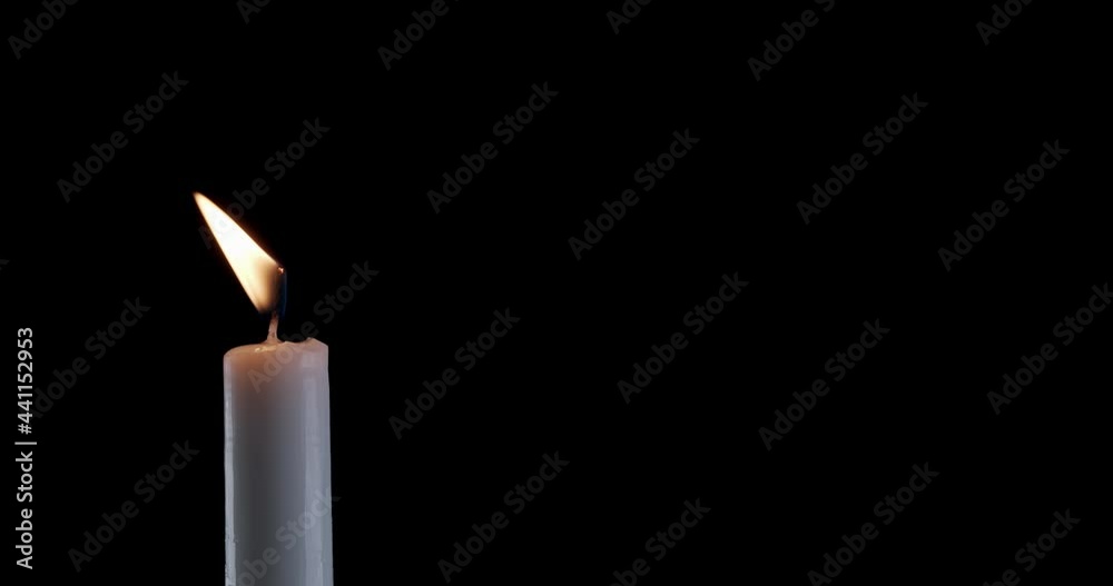 A single white candle burning. The wind tries to put out the flame, but ...