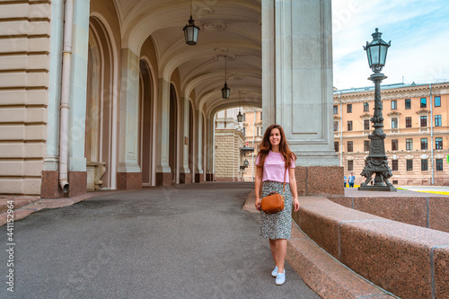 A young woman in a skirt walks in the center of St. Petersburg